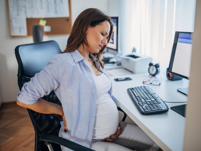 Pregnancy Aches & Discomfort Pregnant woman with back pain at desk