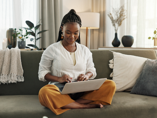 Woman sitting on her couch researching on her laptop Woman sitting on her couch researching on her laptop