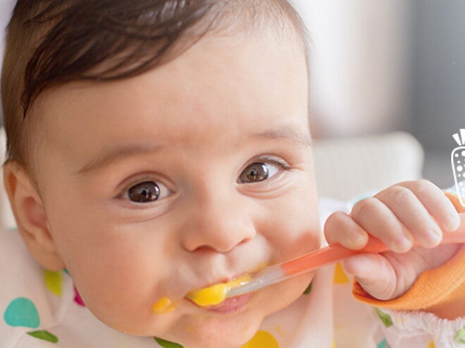 Infant grinning and eating puree. Infant grinning and eating puree.