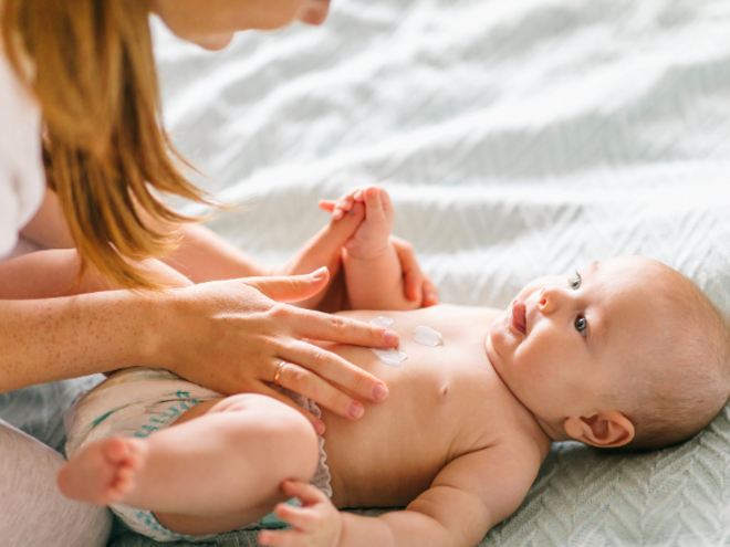 Mother massaging baby laying down with cream Mother massaging baby laying down with cream