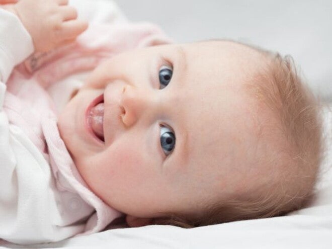 Baby lying down on bed with cradle cap on head Baby lying down on bed with cradle cap on head
