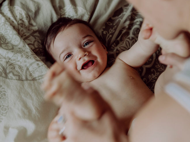 Baby smiling on a bed with his mother Baby smiling on a bed with his mother