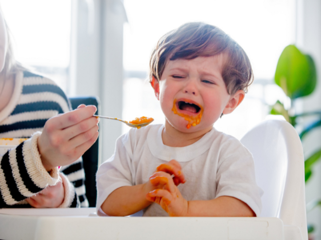 Mother feeding upset toddler boy with spoon Mother feeding upset toddler boy with spoon