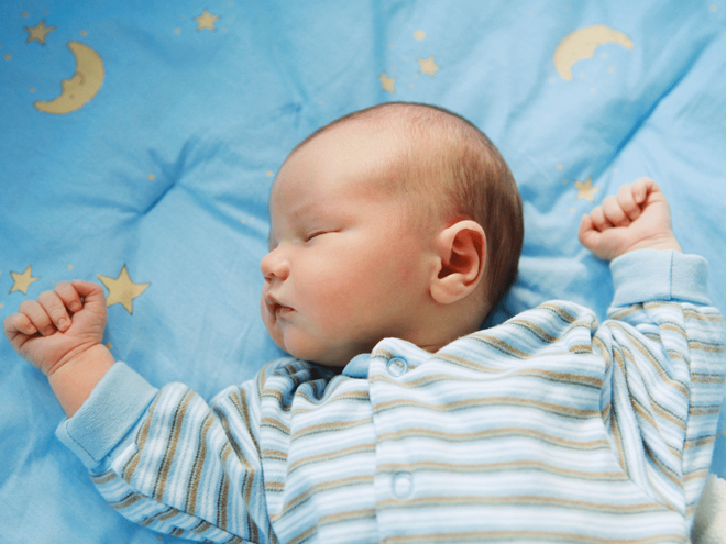 Young baby sleeping on a blanket with moon and stars