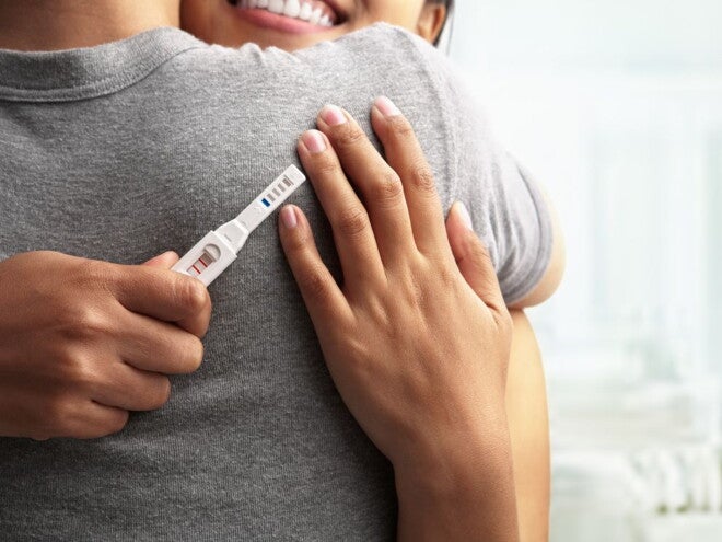 couple hugging with a positive pregnancy test in their hand couple hugging with a positive pregnancy test in their hand