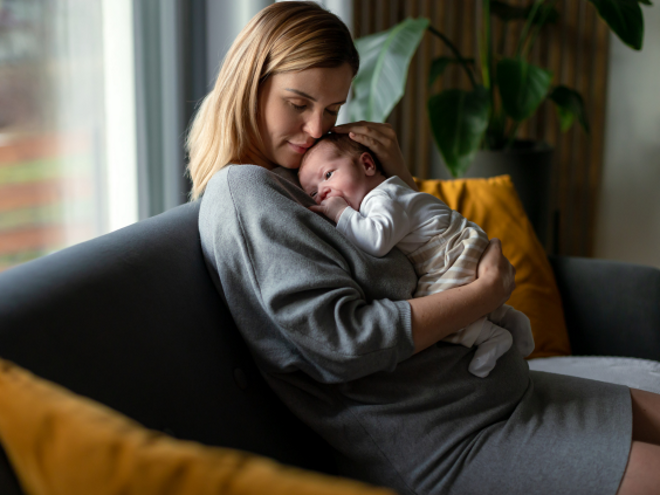 Mother holding her baby on the lounge cuddling Mother holding her baby on the lounge cuddling
