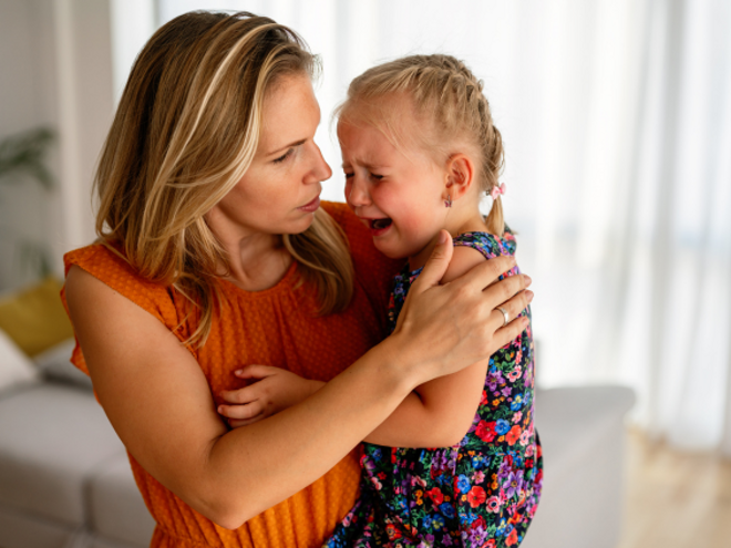 Woman holding her crying daughter Woman holding her crying daughter
