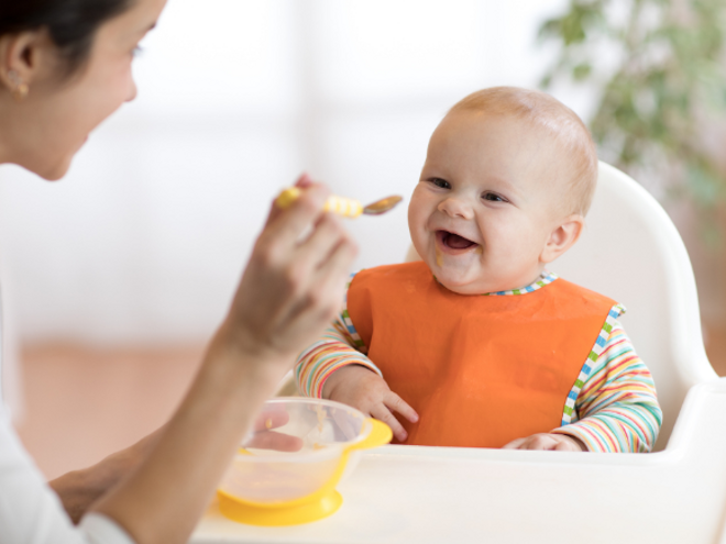 Mother feeding happy baby puree on a spoon Mother feeding happy baby puree on a spoon
