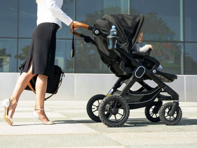 Woman in business attire walking to work with baby in a pram Woman in business attire walking to work with baby in a pram