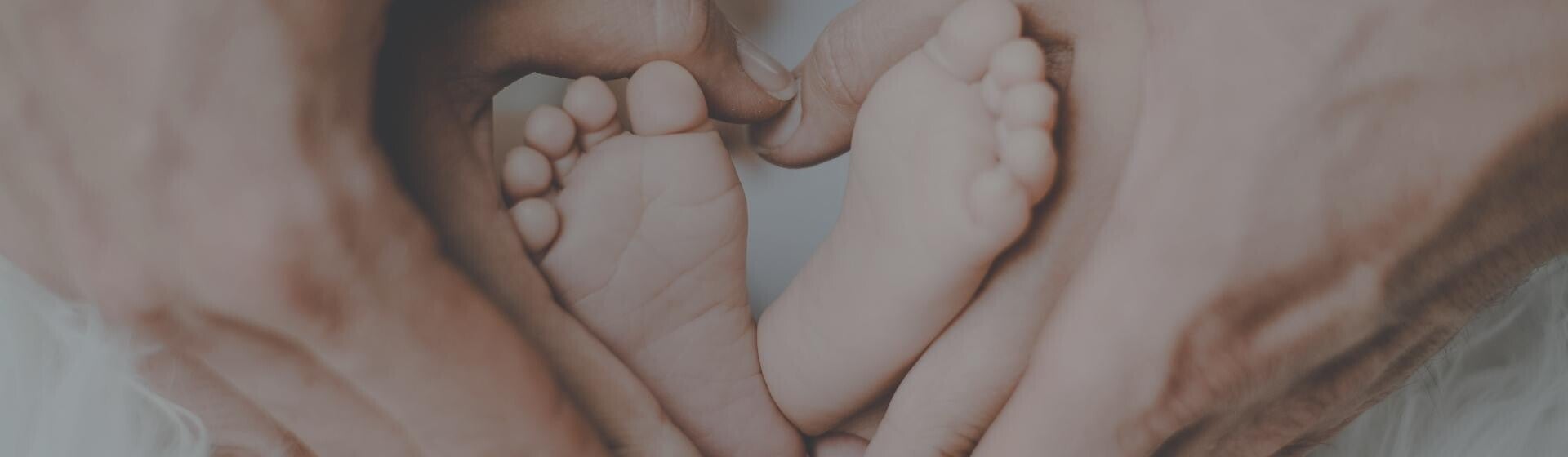 Parents cupping baby's foot in a love heart shape Parents cupping baby's foot in a love heart shape