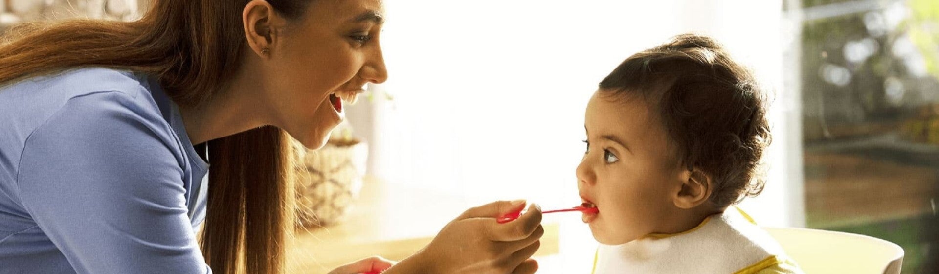 mum feeding baby cereal on spoon mum feeding baby cereal on spoon