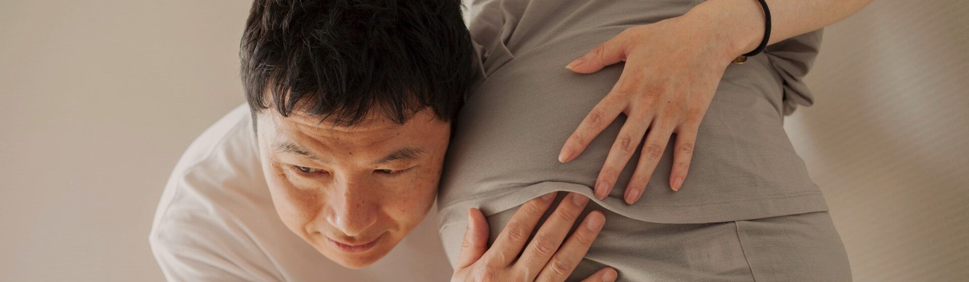 man with ear against pregnant woman's stomach man with ear against pregnant woman's stomach