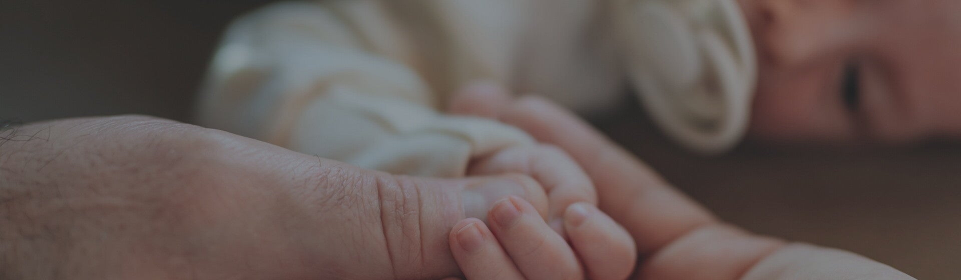 Parents holding their new babies hand while they lie down Parents holding their new babies hand while they lie down