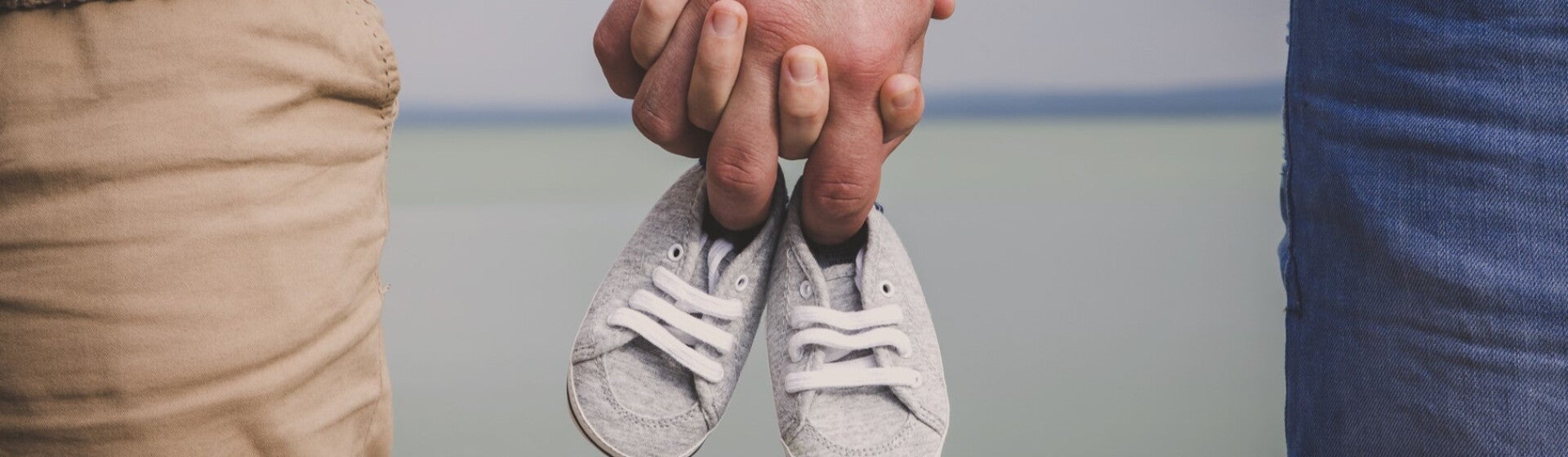 man and woman holding baby shoes in hands man and woman holding baby shoes in hands