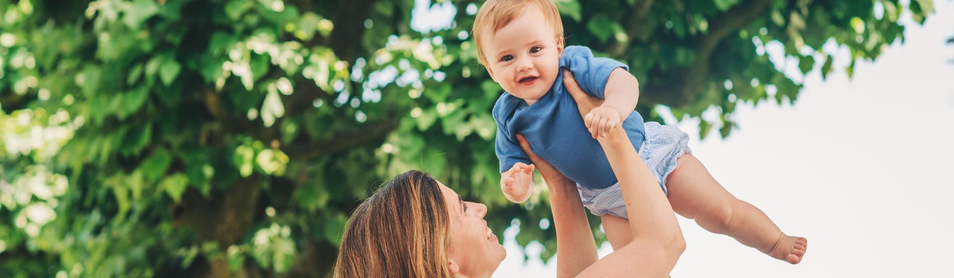 Mother holding baby in the air Infront of trees Mother holding baby in the air Infront of trees