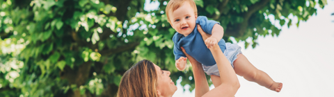 Mother holding baby in the air Infront of trees Mother holding baby in the air Infront of trees